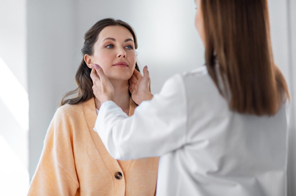 Therapist gently examining a woman’s neck and lymph nodes during a lymphatic assessment for autoimmune support.