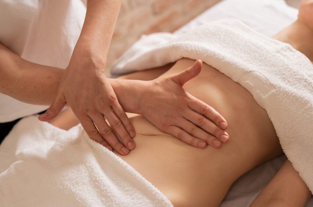 Therapist giving gentle abdominal massage to improve lymph flow, reduce bloating, and support natural body healing