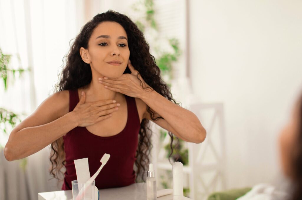 Woman practicing lymphatic self massage on neck at home to prep body for drainage therapy